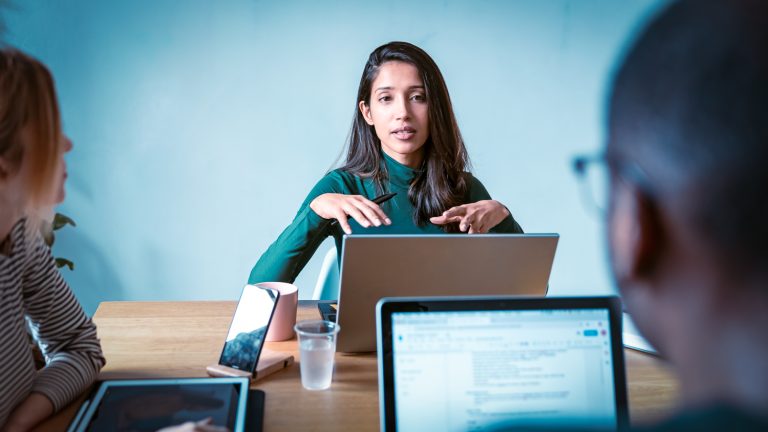 Woman leading a meeting and speaking to her coworkers, presenting a new marketing campaign