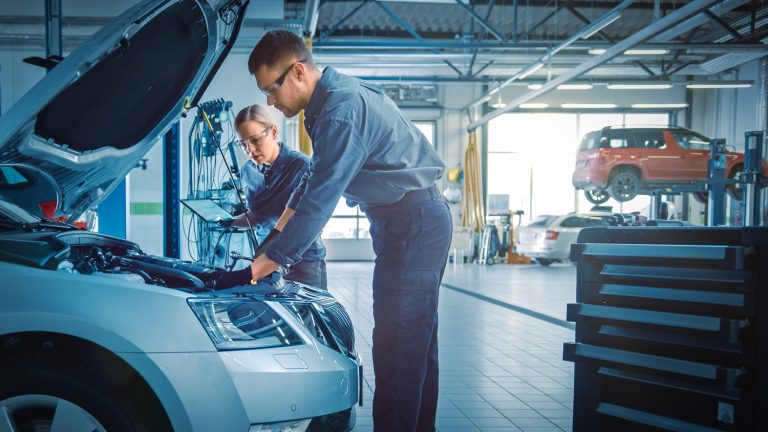 Male and female service technicians fixing a vehicle in the workshop
