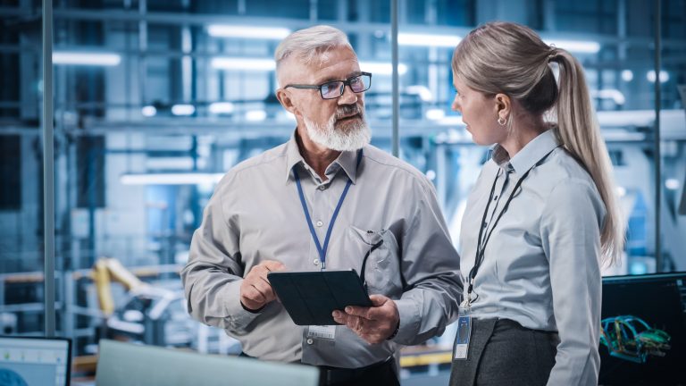 Male service manager speaking to female service manager in the workshop of a car dealership