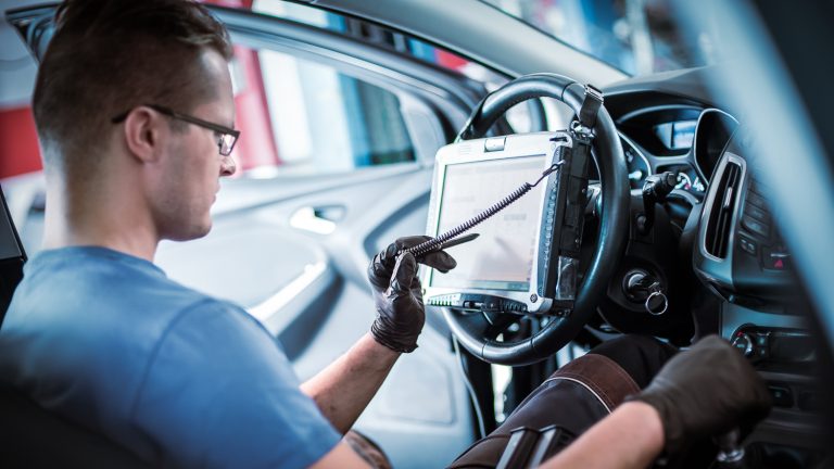 Auto service mechanic fixing a vehicle interior on his tablet