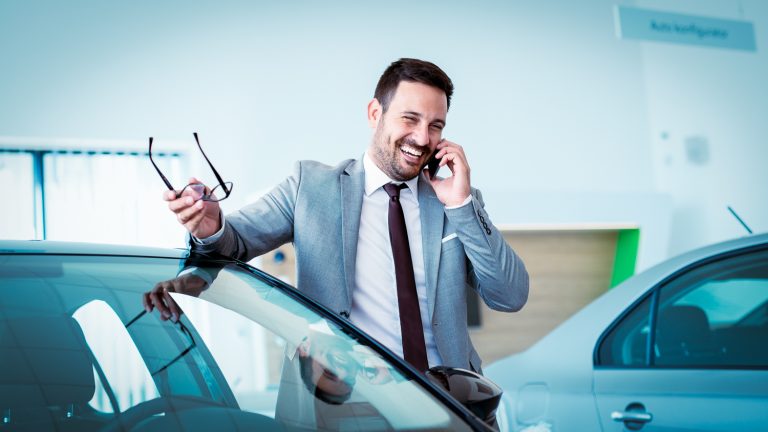 Car salesman talking on a cell phone while in the showroom